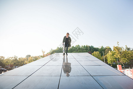 站在屋顶的年轻男城市滑板运动员肖像图片