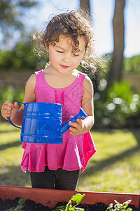 在花园的年轻女孩拿着水壶图片
