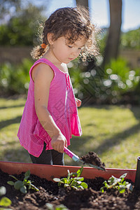 在花园的年轻女孩在挖土图片