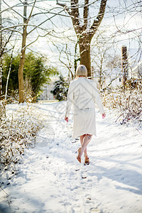 身穿白衣在雪地上行走的年轻女子图片