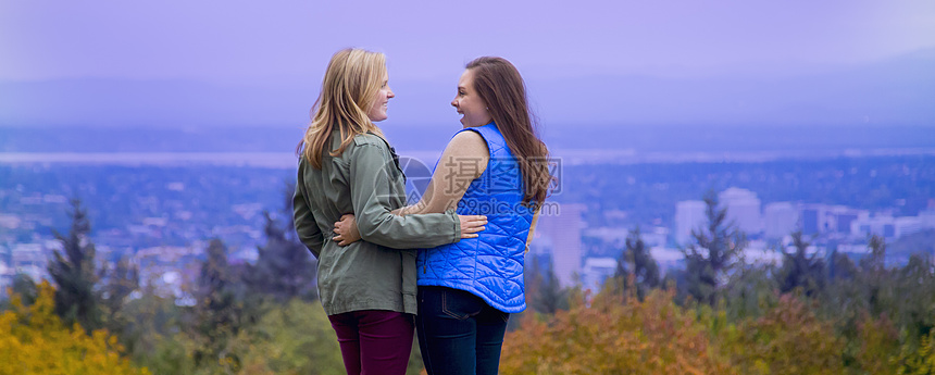 两个年轻女站在山坡上手对微笑着图片