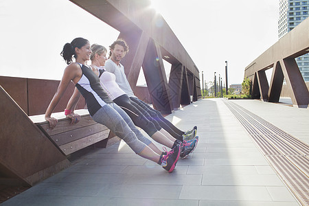 两名女和男在城市步行桥上做热身运动图片