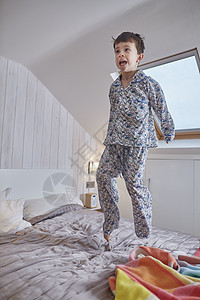 穿着睡衣的男孩在阁楼的床上跳图片