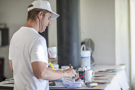 男子将油漆混合在塑料容器中图片