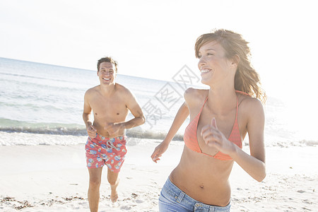 海滩上追逐的年轻情侣图片