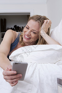 在床上浏览手机短信的成年女人图片