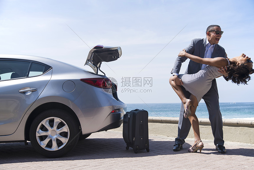带行李的蜜月夫妇在海滩上跳舞图片