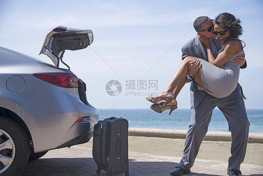 男人在海滩的行李旁抱着女人亲吻她