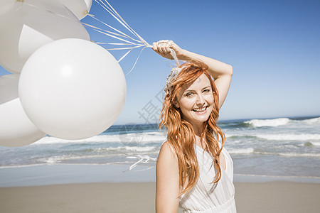 海滩上的红发女人拿着气球微笑图片