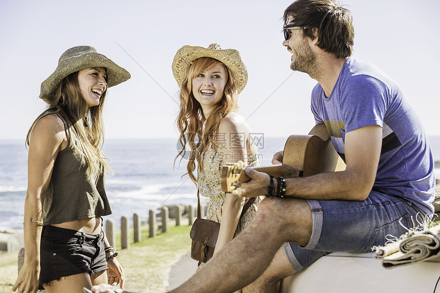 在南非开普敦海岸坐在汽车上弹吉他音乐的成人朋友图片
