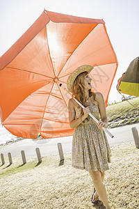在南非开普敦海滩携带红色伞的中成年妇女图片
