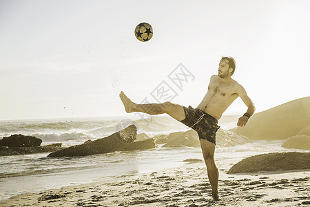 在海滩上中年男子踢足球图片