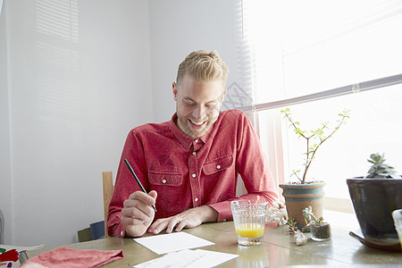 坐在餐桌边写信的年轻人图片素材