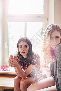 坐在厨房柜台的两名年轻妇女肖像图片