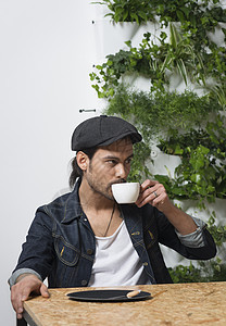 坐在咖啡桌上喝咖啡的年轻男性图片