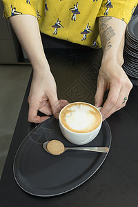 女服务员手拿咖啡馆托盘上的卡布奇诺图片