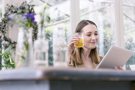 年轻女士拿着平板电脑喝着果汁图片