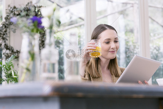 年轻女士拿着平板电脑喝着果汁图片