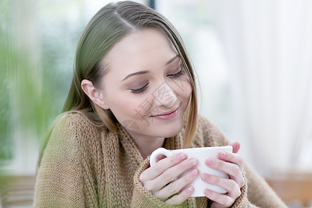 拿着杯子闭眼微笑的年轻女性图片