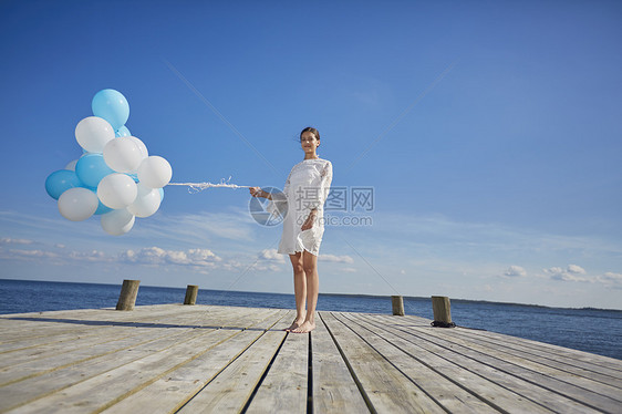 站在木码头拿着一堆气球的年轻女人图片