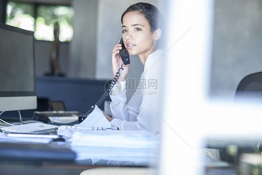 在办公服务台的电话聊天的女商人图片