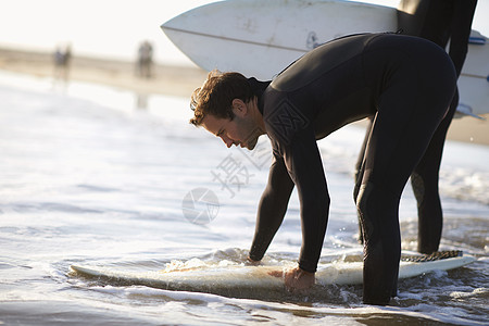 美国加利福尼亚州威斯海滩准备上冲浪板的男者图片
