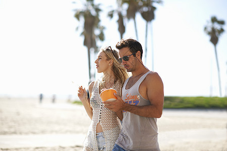 在美国加利福尼亚州威斯海滩散步吃冰淇淋的年轻情侣图片
