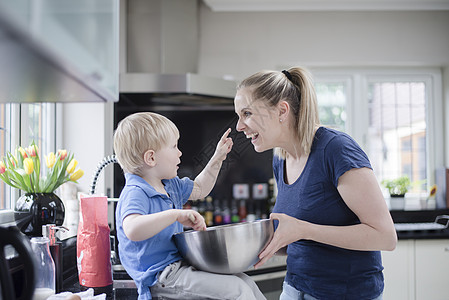 母亲和儿子在做烘烤时儿子在母亲鼻上涂面糊图片