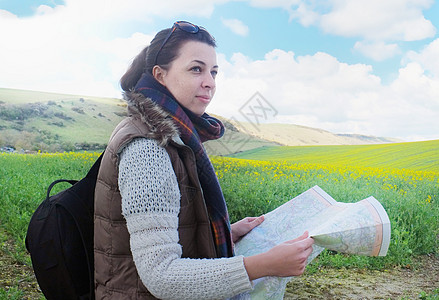站在田野中拿着地图的年轻女士图片