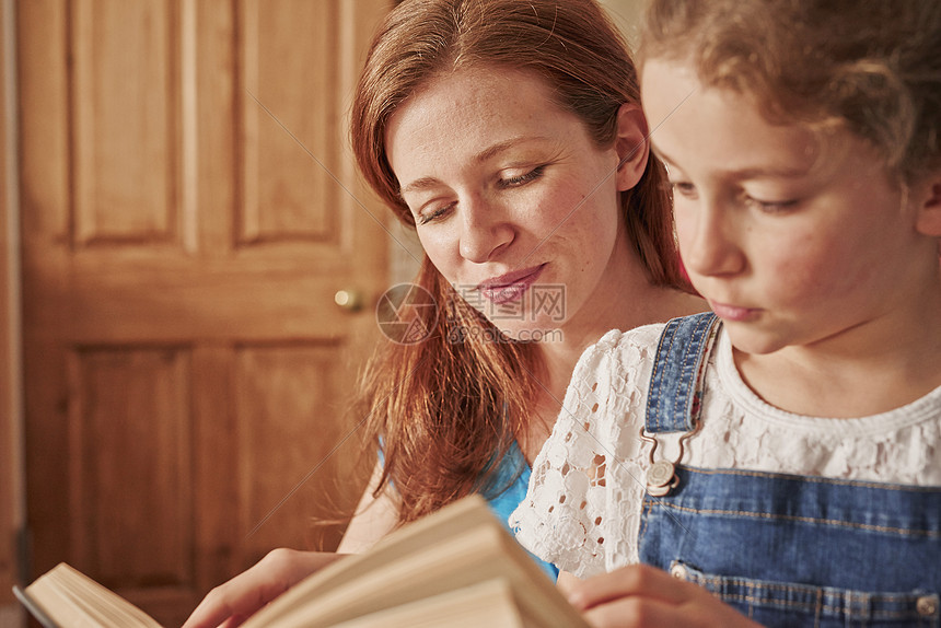 女孩与母亲在客厅一起阅读书图片