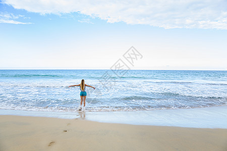 多米尼加勒比海滩上张开双臂的年轻美女的背影图片