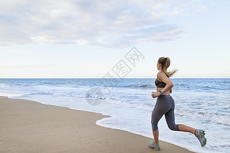 在多米尼加勒比的海滩上跑步的年轻女跑者图片