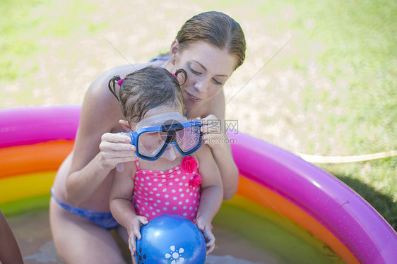母亲在充气池里给女儿戴上护目镜图片