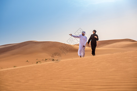 阿拉伯联合酋长国迪拜的沙漠丘穿着传统中东部服装的夫妇图片