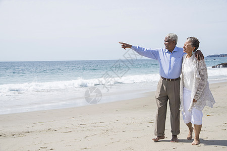 老年夫妇一起在海滩上漫步看风景图片