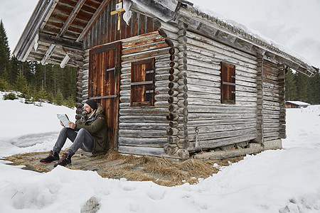 坐在冬季木屋外的年轻人图片