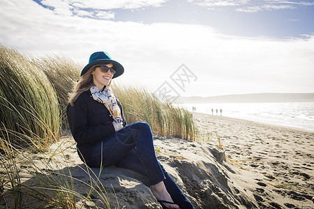 美国加利福尼亚州迪伦海滩沙丘上戴着帽子和太阳眼镜的女人图片