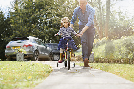 父亲教女儿在街上骑自行车图片