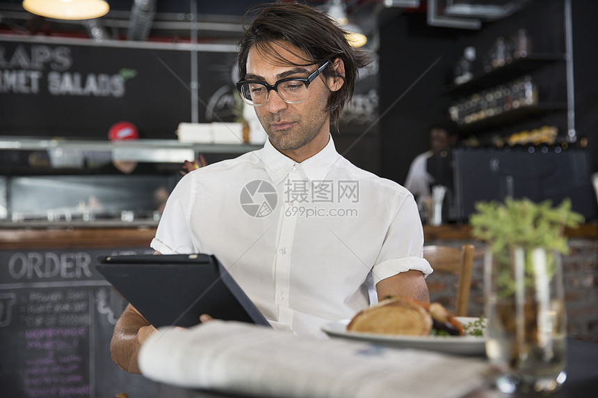 咖啡店男店员看着平板电脑图片