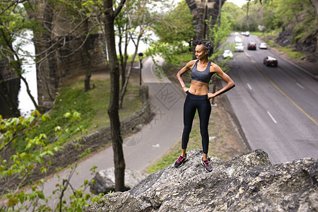 身着运动服装站在公路岩石上的妇女图片