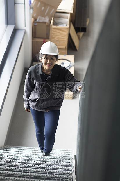 成年女子戴着安全帽在工厂楼梯上行走图片