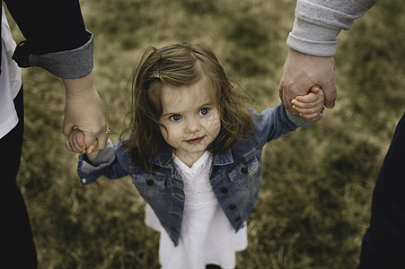 小女孩牵着父母的手在户外行走图片