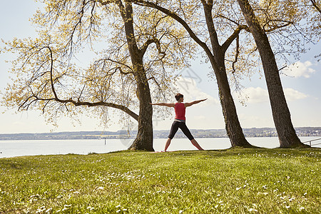 在湖边草坪上做瑜伽的女性图片