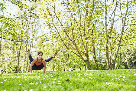公园草坪上做瑜伽的年轻女性图片