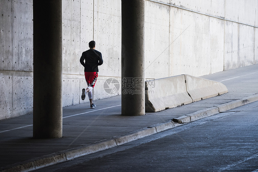 在城市地下通道跑步的年轻男子图片
