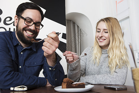 在咖啡厅桌边吃巧克力蛋糕的快乐情侣图片
