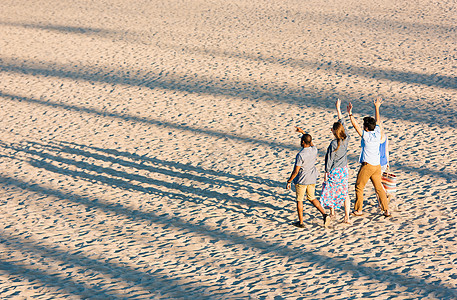 四位成年朋友在美国加利福尼亚州的海滩上挥舞图片