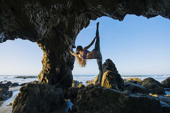 年轻女舞者在岩石上高抬腿图片