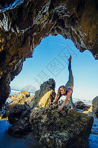 年轻女舞者在岩石上高抬腿背景图片