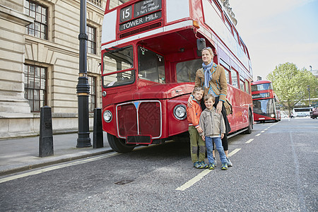 母亲和儿子站在红色巴士前图片